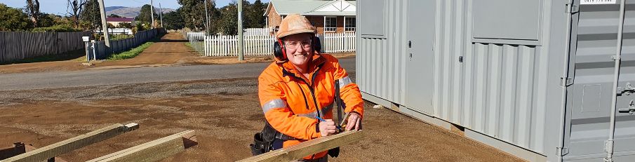 Sophie Russell at work on a building site. She is wearing high-vis and working on a piece of wood.